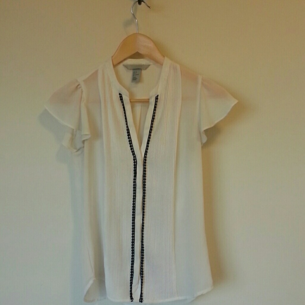 Cream sheer blouse with black trim.